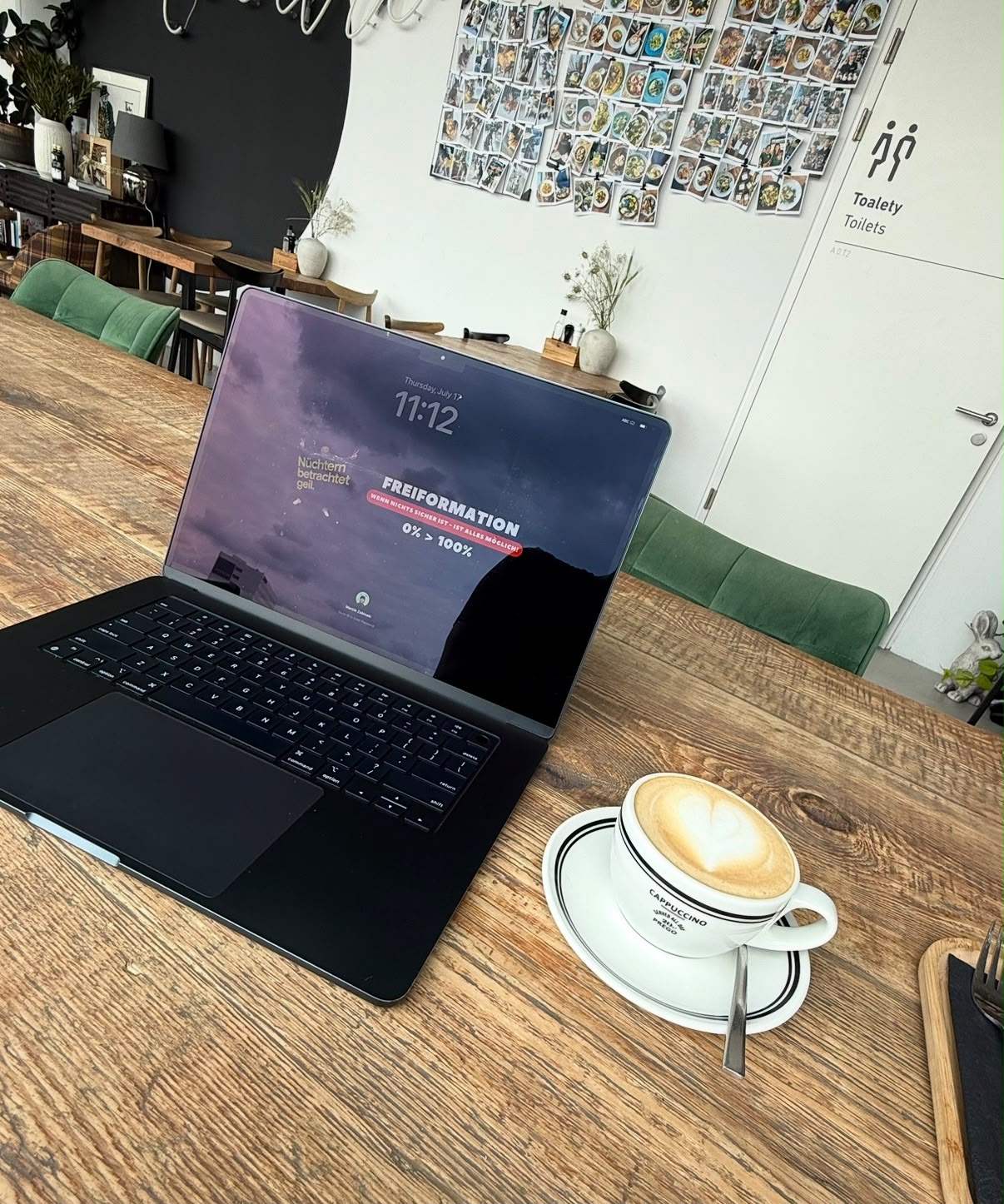 Marcins Laptop mit Kaffee auf einem Holztisch im Café