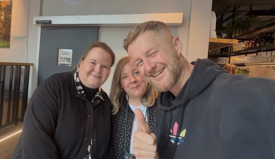 Marcin macht ein Selfie mit Sabine und ihrer Begleitung in einem Café