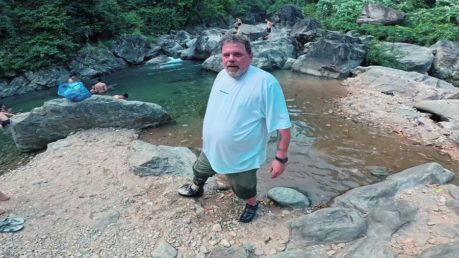 Ulli mit Beinprothese im Freiformation-Shirt am Wasserfall im Dschungel